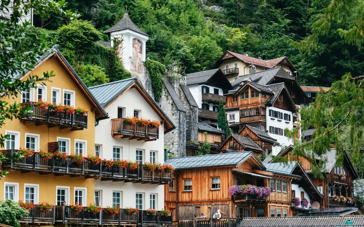 Hallstatt houses with flower boxes on wooden balconies, a forested slope behind