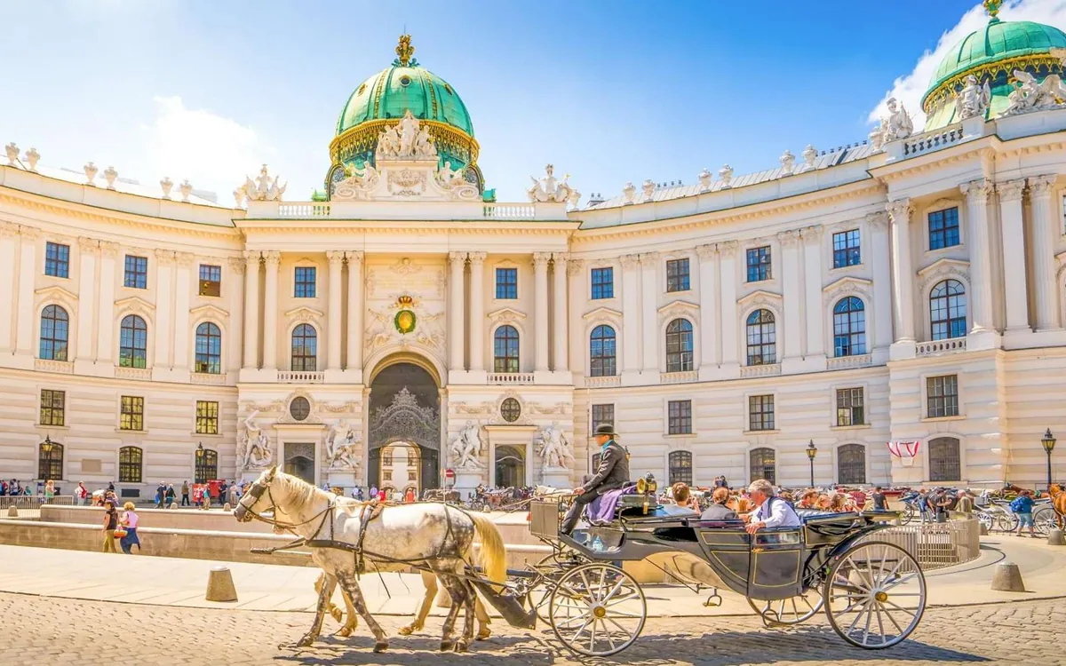The domed gate of the Hofburg Palace with a horse-drawn fiaker passing in front