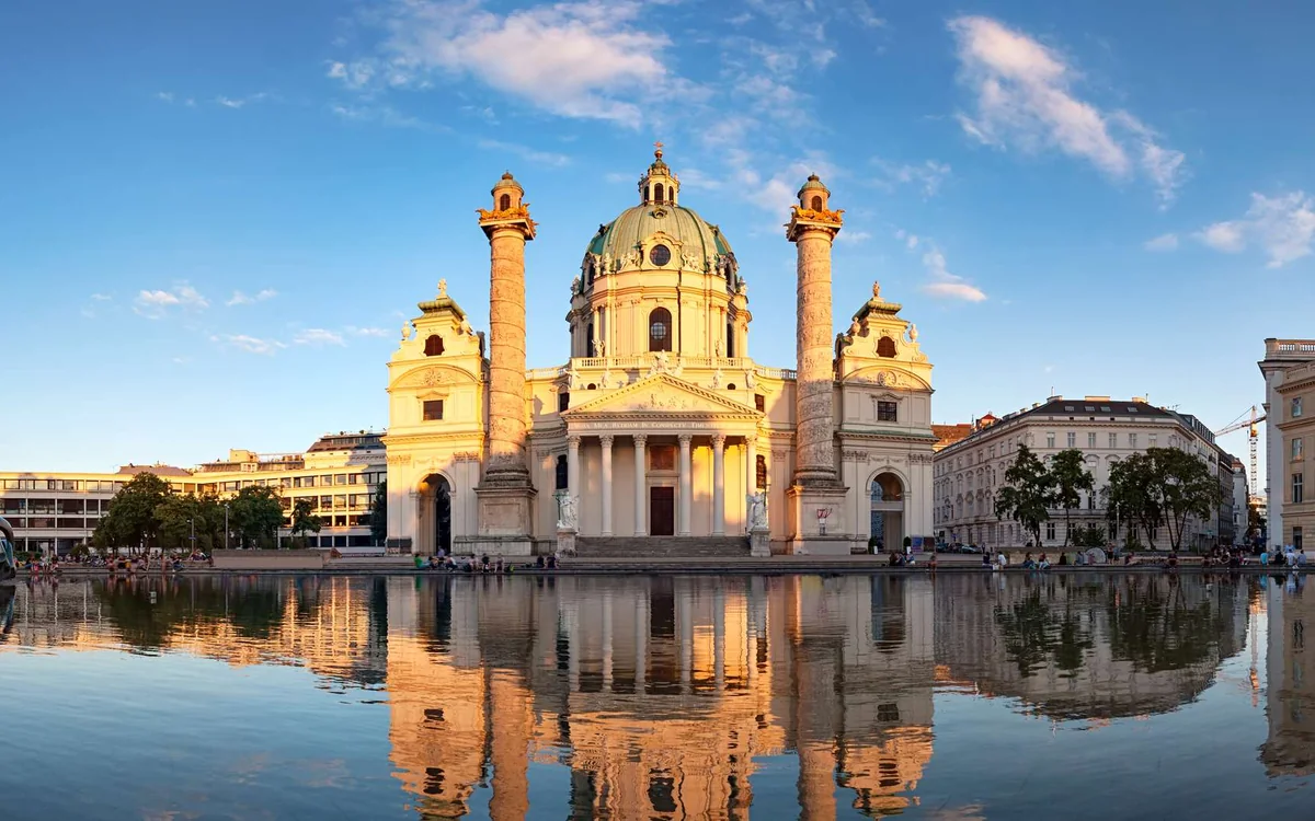 The baroque Karlskirche with its green dome and two columns reflected in a pool