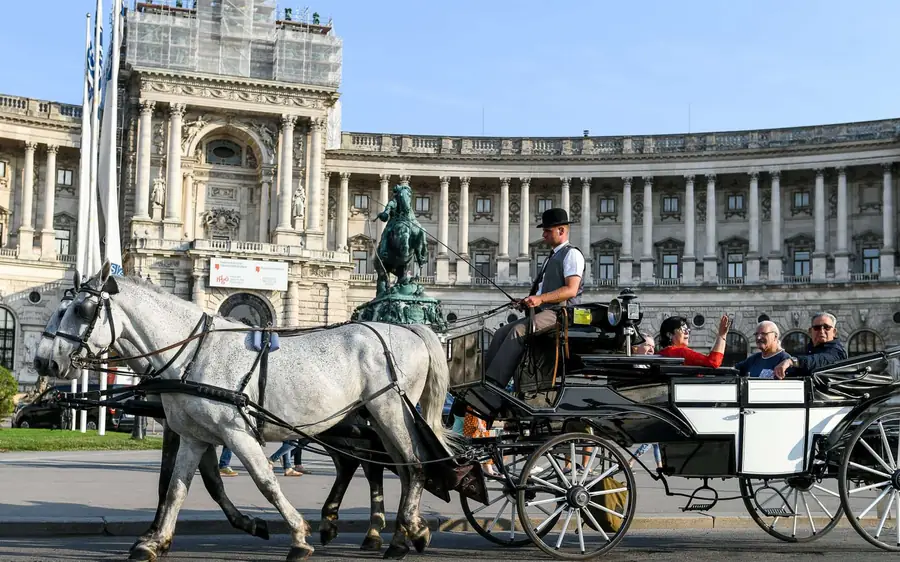 A two-horse fiaker passing the colonnaded wing of the Hofburg
