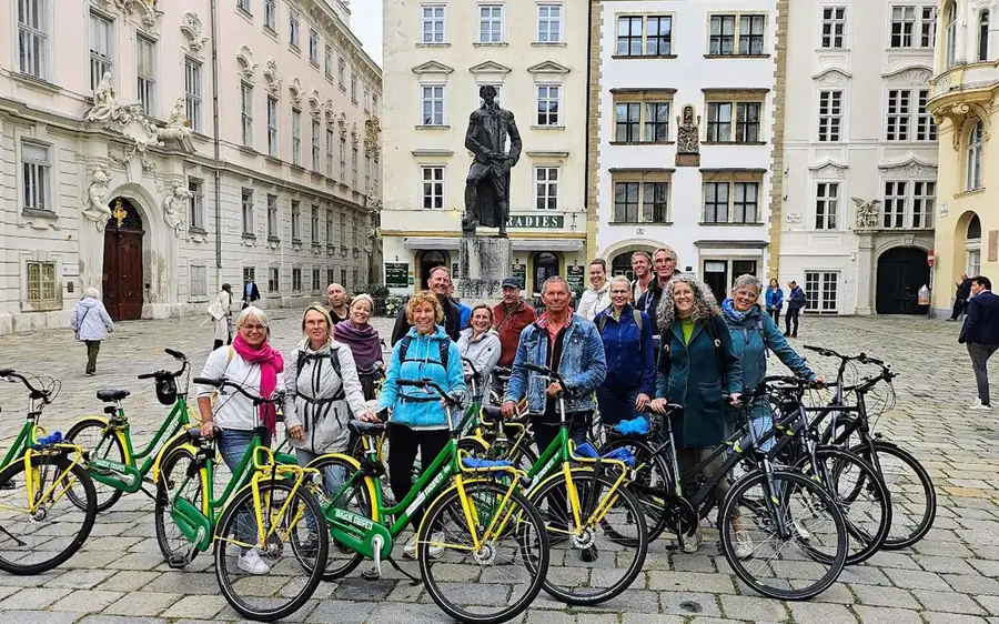 A group with green and yellow bikes on a square beside a statue
