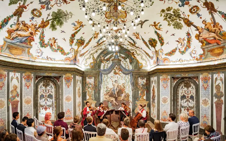 A string ensemble playing under a painted ceiling in a small hall