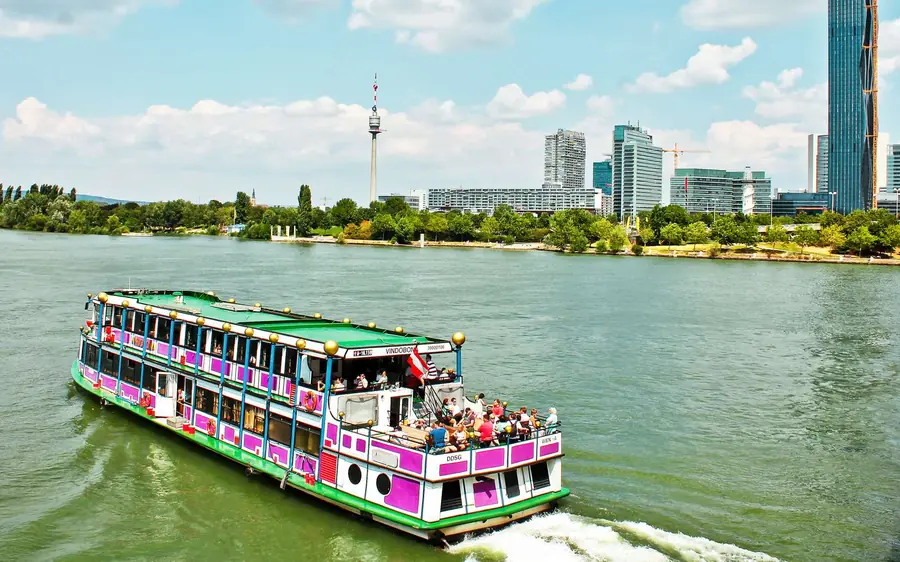 A pink paddle-style boat with passengers on the Danube