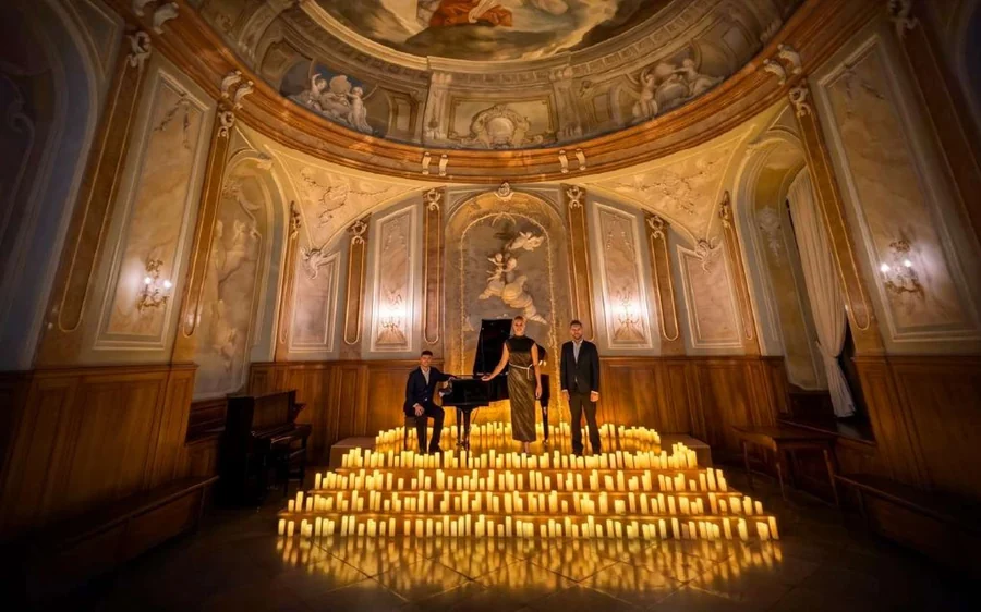 Singers and a pianist on a stage covered with candles