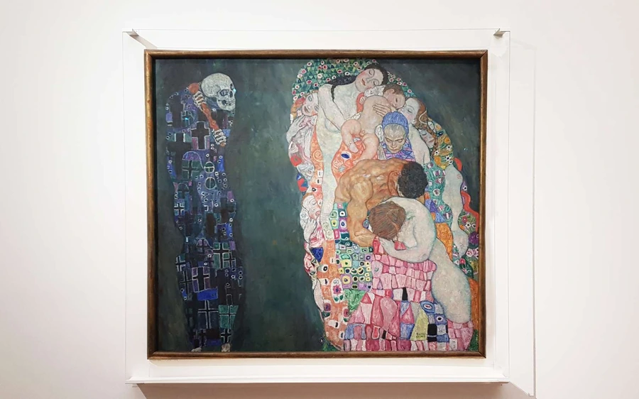 A Gustav Klimt painting with richly patterned figures on a gallery wall