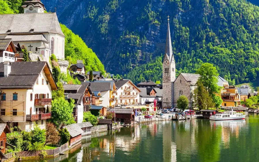 Hallstatt church spire and lakeside houses below wooded slopes