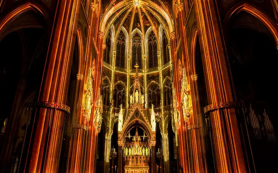 The Gothic nave of Votivkirche lit in orange and gold