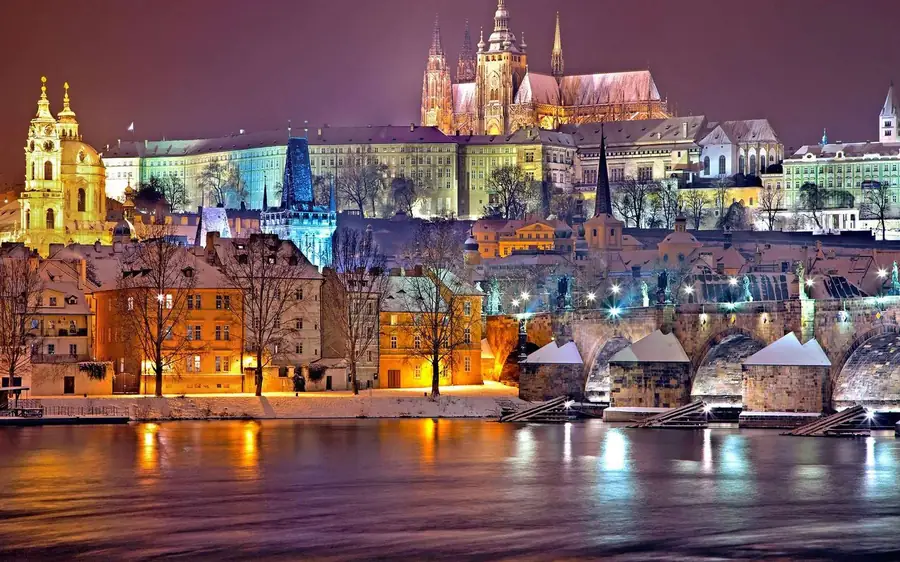 Prague Castle and the Charles Bridge lit up above the river at night