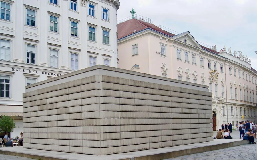 A concrete monument on a square framed by pale old buildings