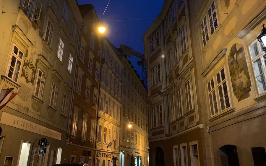 A narrow lane between old houses lit by street lamps at night