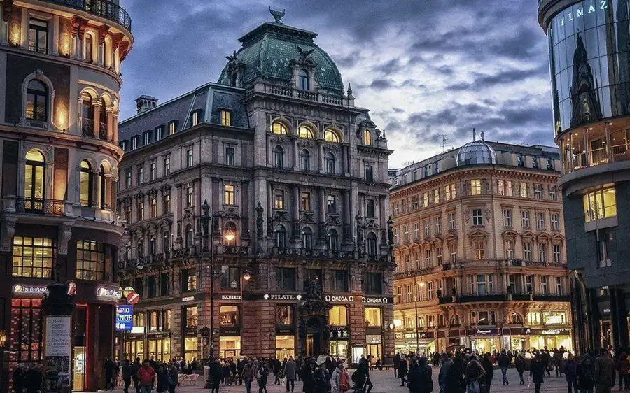Grand corner buildings on a busy old-town square at dusk