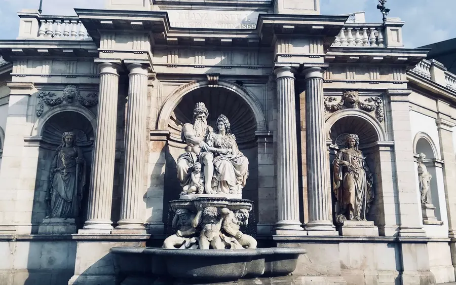 A marble fountain with sculpted figures set in a columned wall