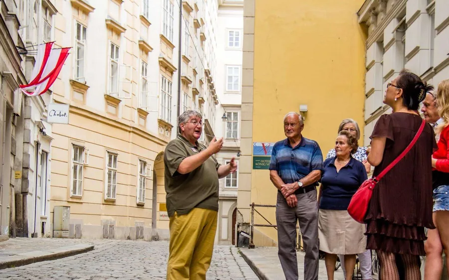 A guide talking to a group on a cobbled lane between yellow houses