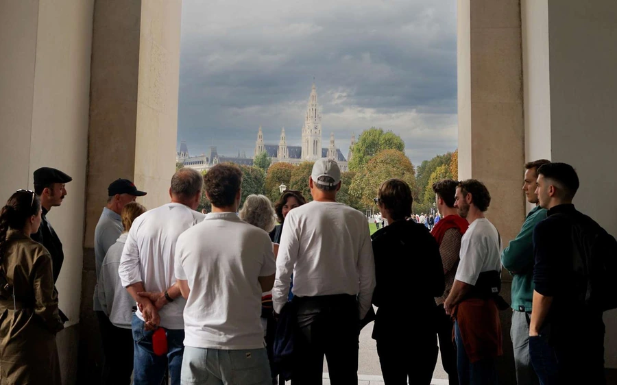 A tour group under an archway looking out towards a Gothic tower