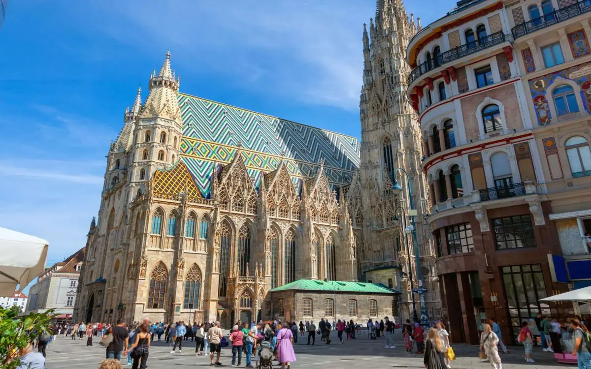 The Gothic tower and patterned tile roof of St. Stephen’s Cathedral above a busy square
